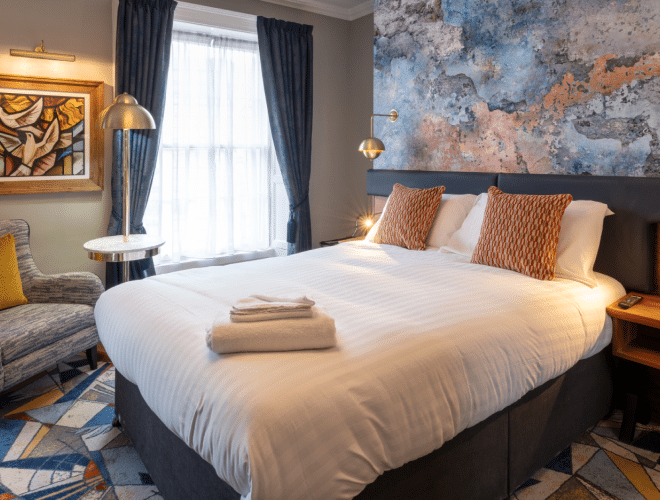 Freshly made bed with towels on corner within a stylish hotel room