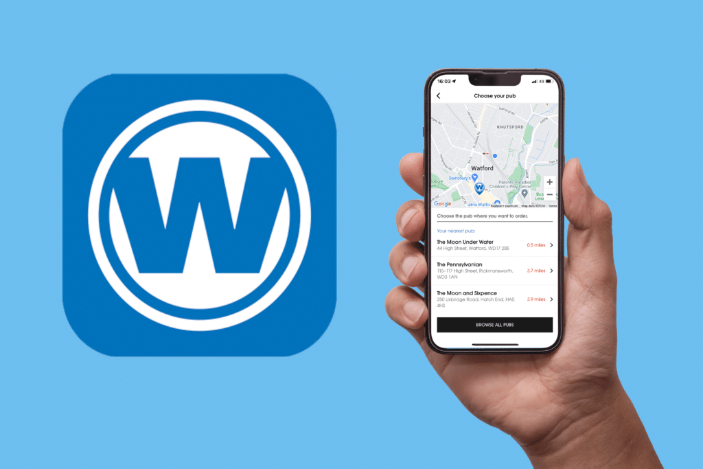 Hand holding a mobile phone showing the Wetherspoon app displaying a map of local pubs