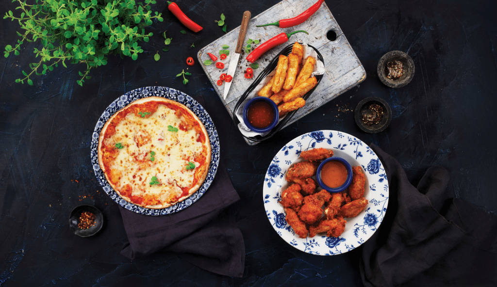 3 small plates containing a small margherita pizza, halloumi chips and chicken wings with side dips